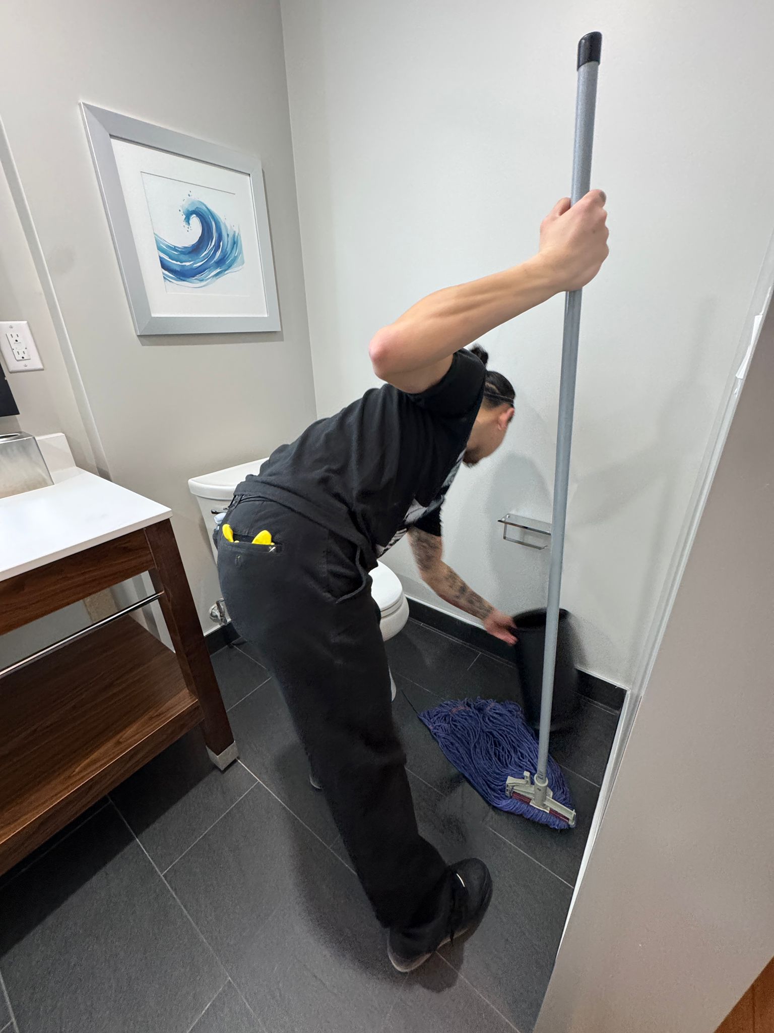 Worker mopping bathroom corner